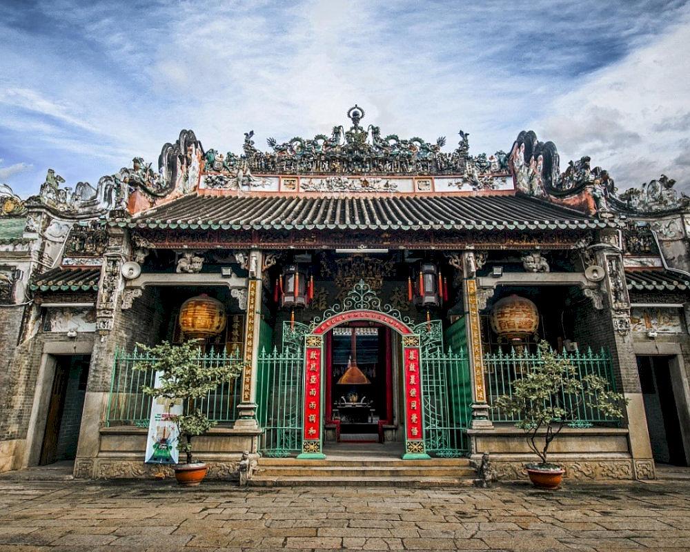 The ornate rooftop of Ba Thien Hau Pagoda adorned with ceramic dragons and historical murals, standing out against the sky